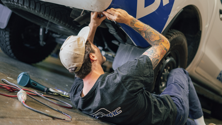 Worker cutting wrap under a vehicle