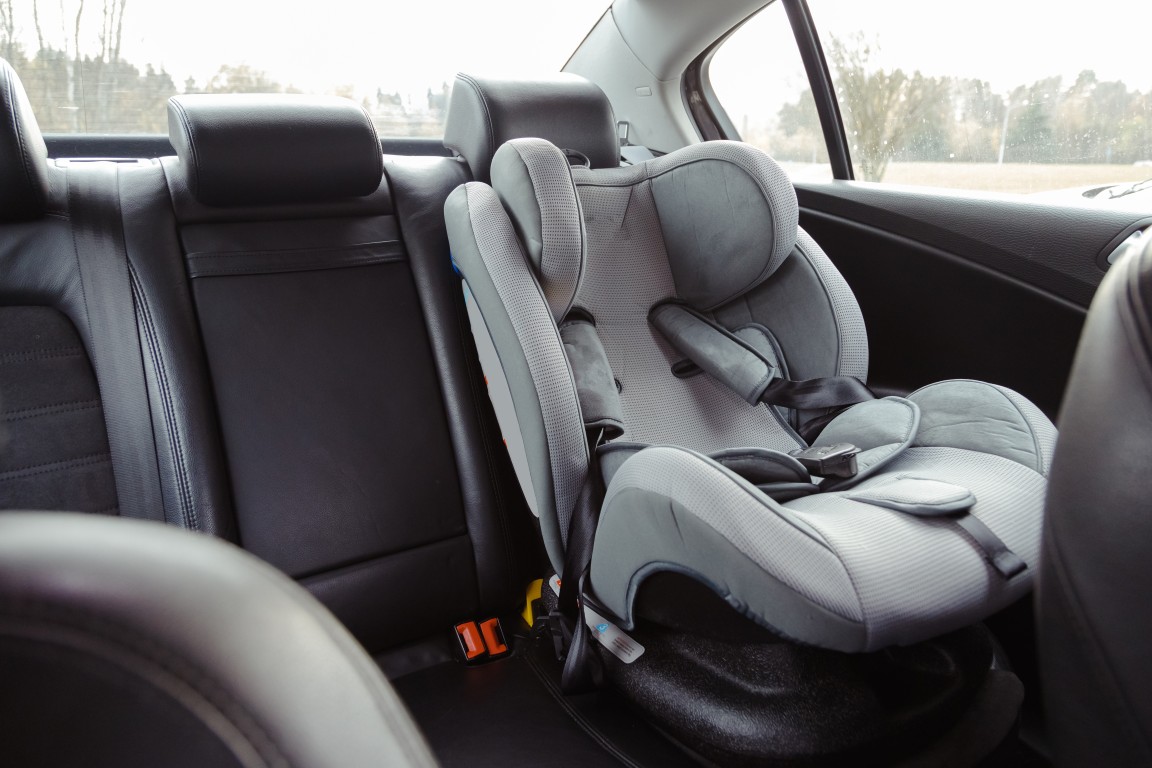 Accredited fitter installing a child car seat and checking the top tether